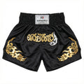 Black Muay Thai shorts with gold and white designs on a white background
