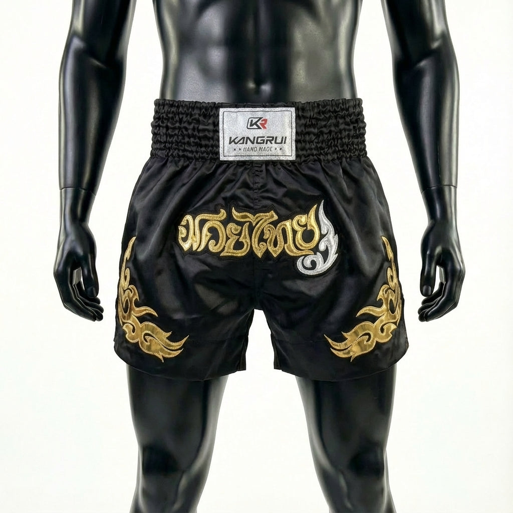 Black Muay Thai shorts with gold designs on a mannequin against a white background