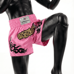 Pink boxing shorts with black designs and a visible brand label on a mannequin.