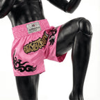Pink boxing shorts with black designs and a visible brand label on a mannequin.