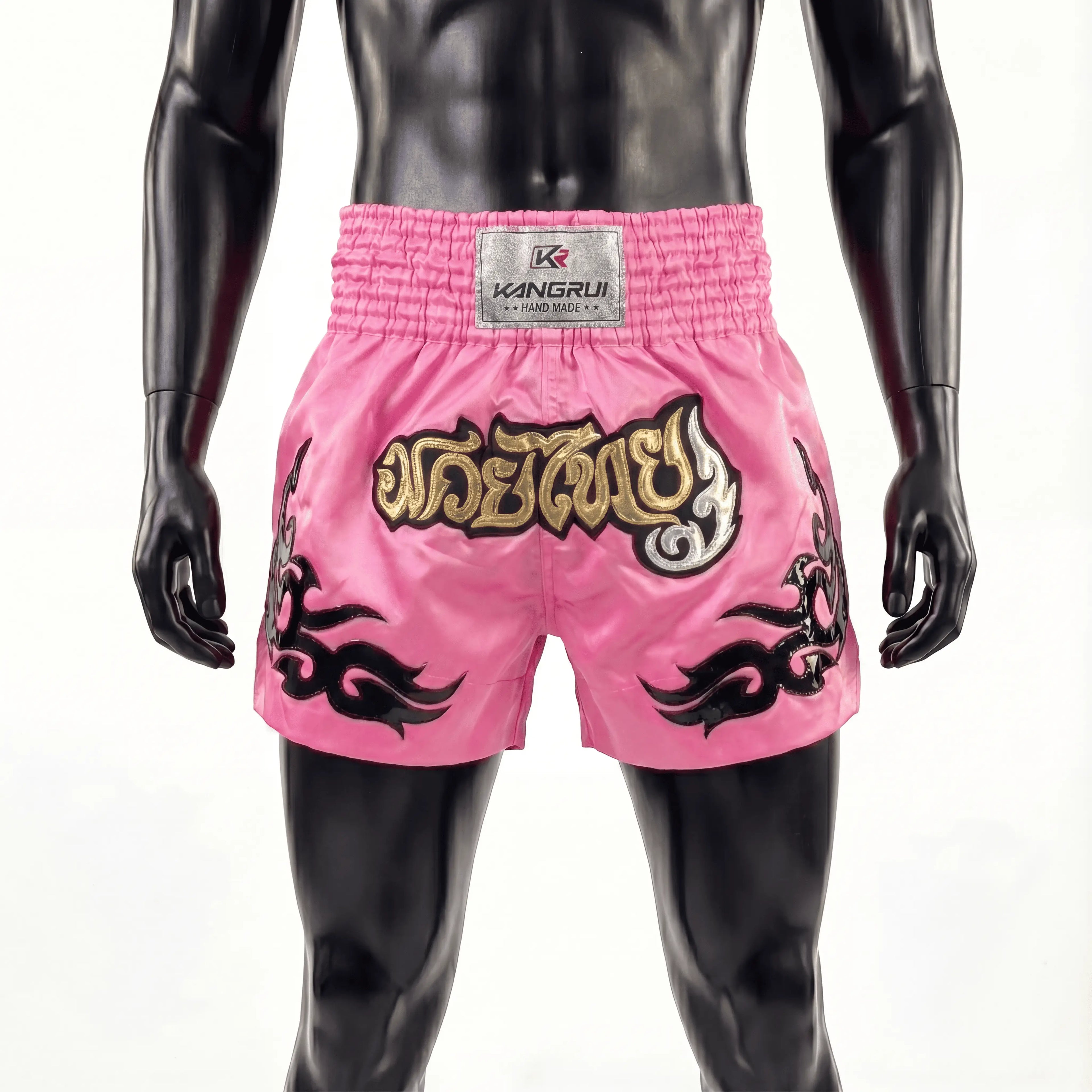 Pink boxing shorts with black and gold designs on a mannequin against a white background