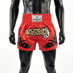Red boxing shorts with black and gold designs on a mannequin against a white background