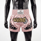 Pink boxing shorts with black designs and a visible brand label on a mannequin against a white background.